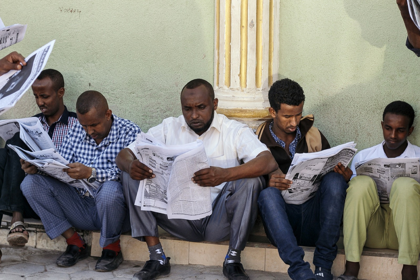Division Multiplied, photo 06. Men read newspapers outside a telecom office in downtown Hargeisa.